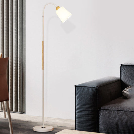 Weiße Stehlampe mit Holzdetail neben schwarzem Sofa und hellgrauen Vorhängen