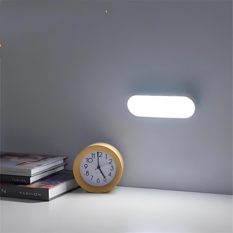 Weißes Wandlicht über Uhr auf Nachttisch, leuchtend im dunklen Raum