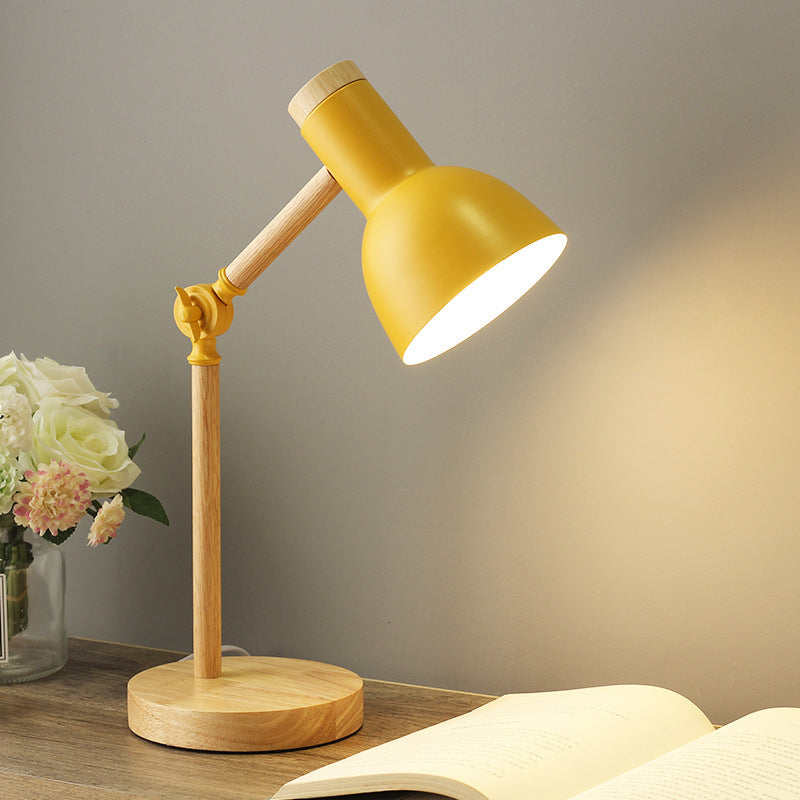 Gelbe Retro-Schreibtischlampe mit Holzarm und offenem Buch im Vordergrund