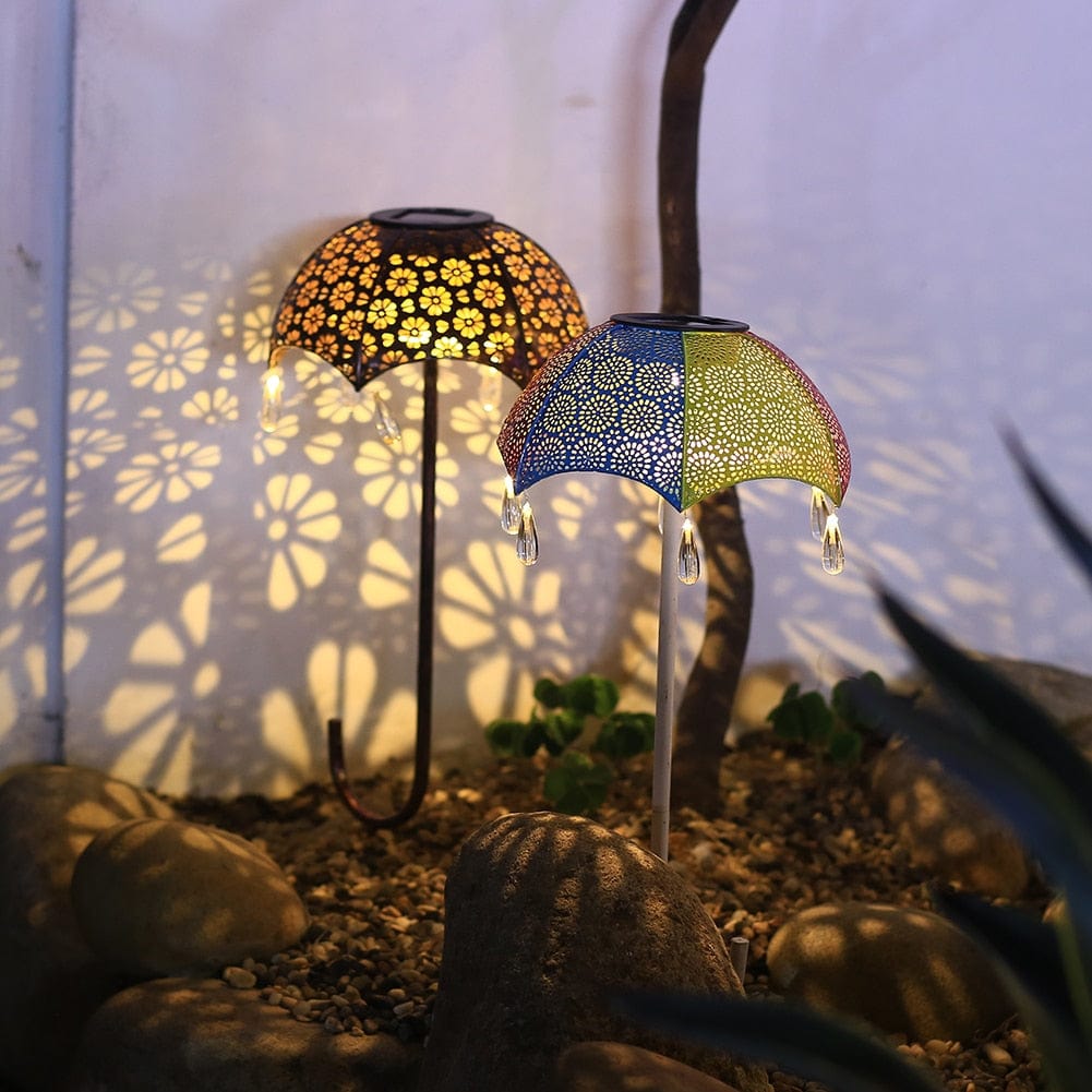 Zwei Schirm-Solarleuchten mit filigranem Muster projizieren florale Schatten im Garten