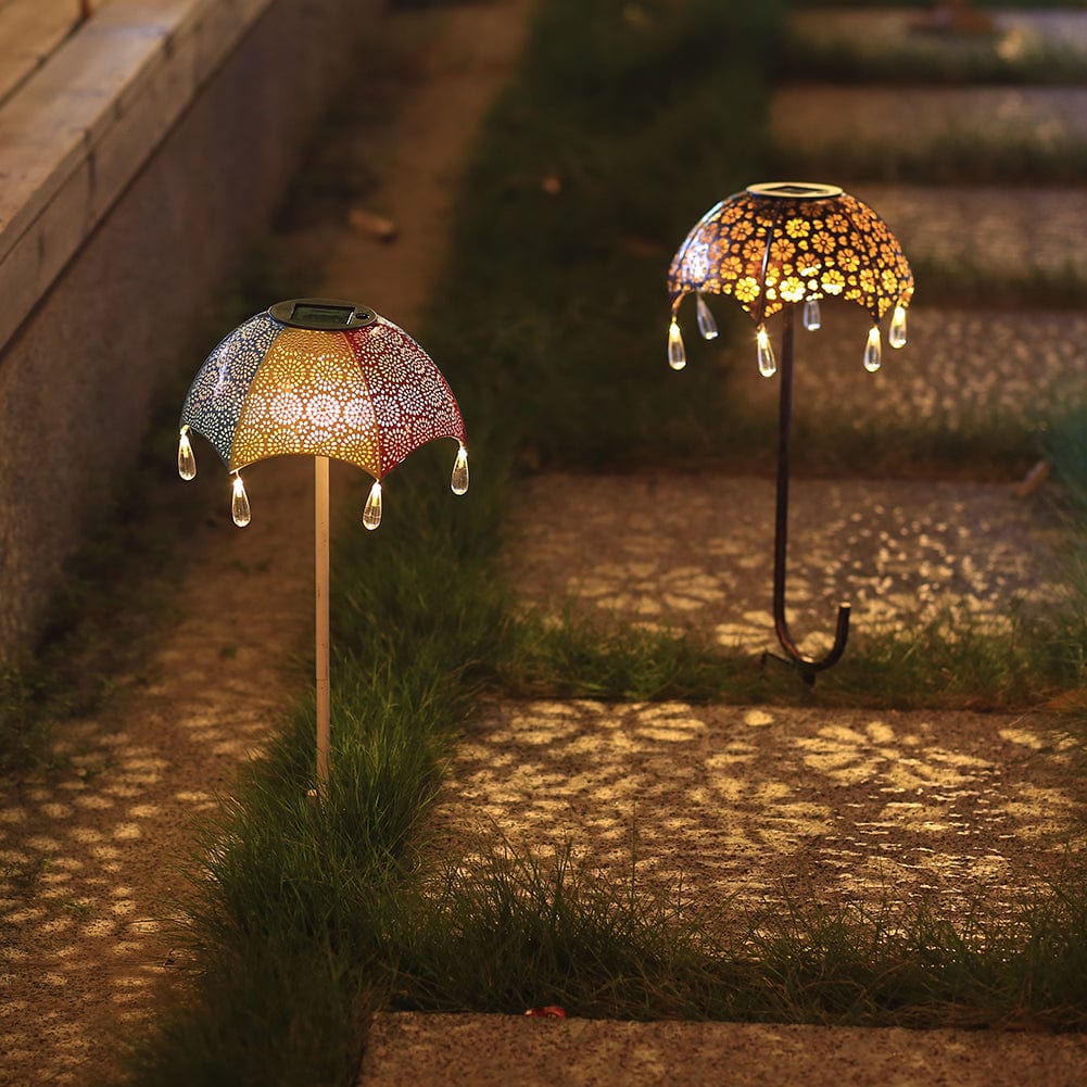 Gartenweg mit zwei bunten Regenschirm-Solarleuchten, die Muster auf den Boden werfen