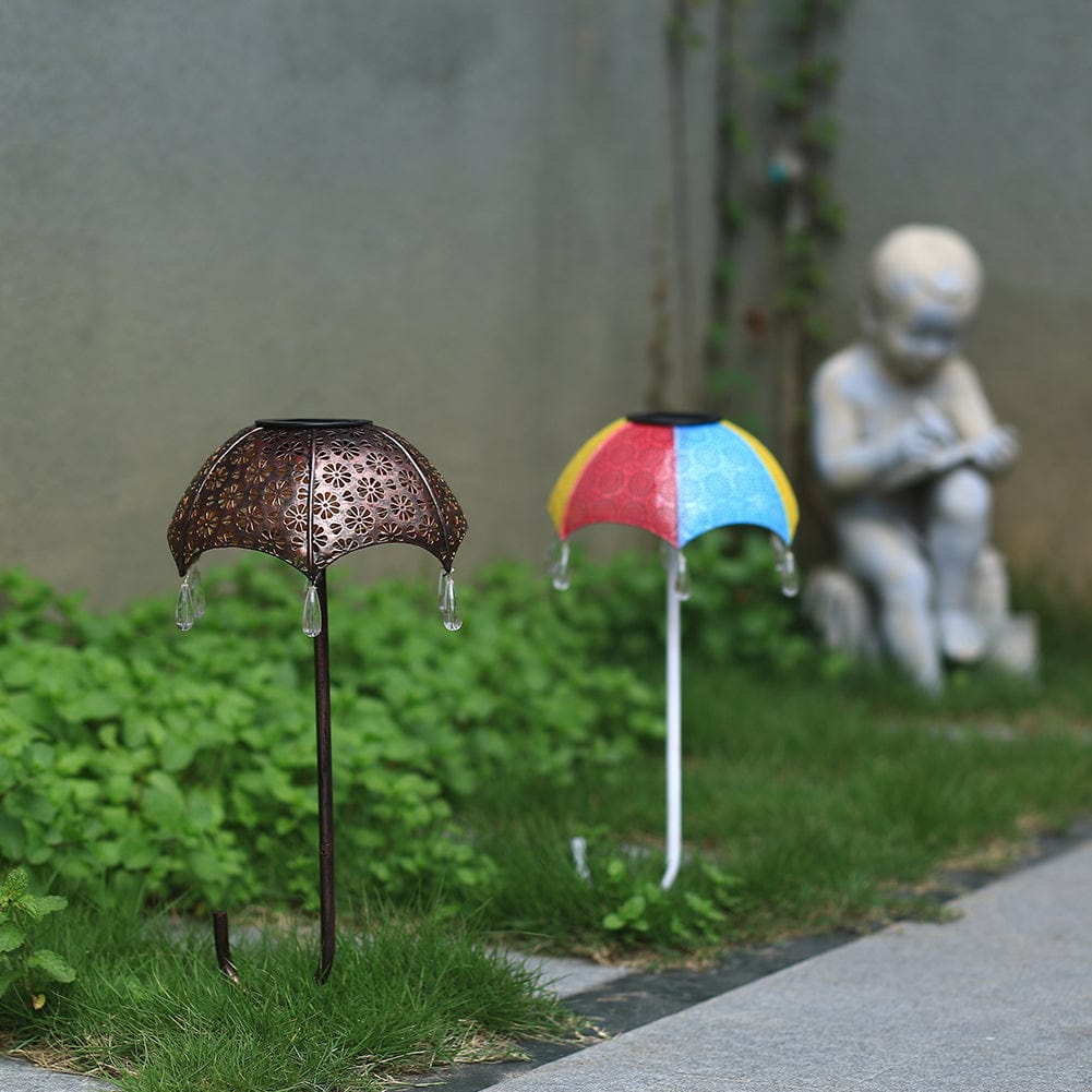 Eine braune und eine bunte Schirmlampe nebeneinander auf Gartenweg