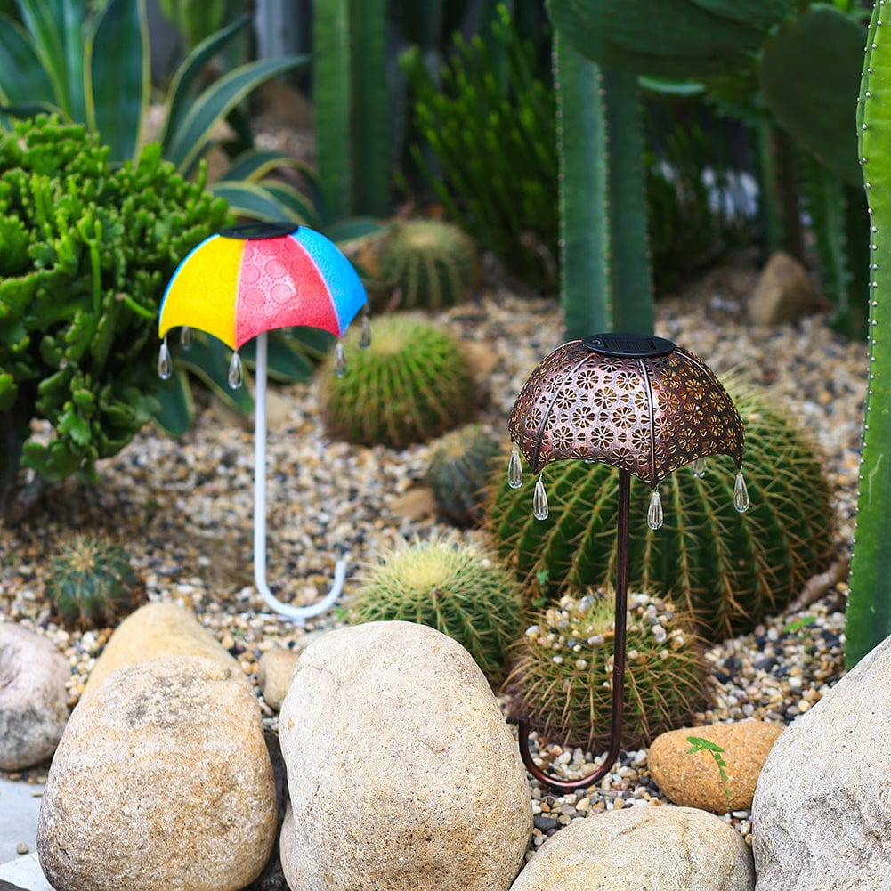 Bunte Regenschirm-Gartenlampe bei Kakteen und Steinen im Beet