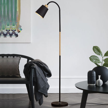 Schwarze Bogenlampe mit Holzdetail neben schwarzem Tisch und Wanddeko