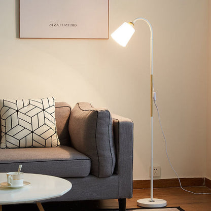 Weiße Leselampe mit Holzarm neben grauem Sofa und rundem Tisch