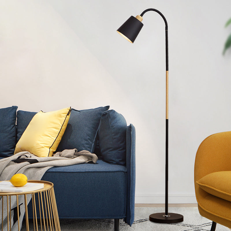 Schwarze Stehlampe mit Holzdetail neben blauem Sofa und gelbem Kissen