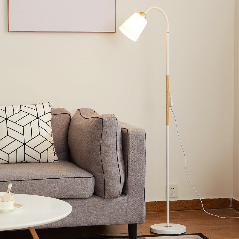 Weiße Stehlampe mit Holzakzent neben grauem Sofa in heller Wohnumgebung