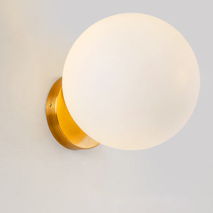 Runde Wandleuchte mit mattweißer Glaskugel und goldener Wandhalterung
