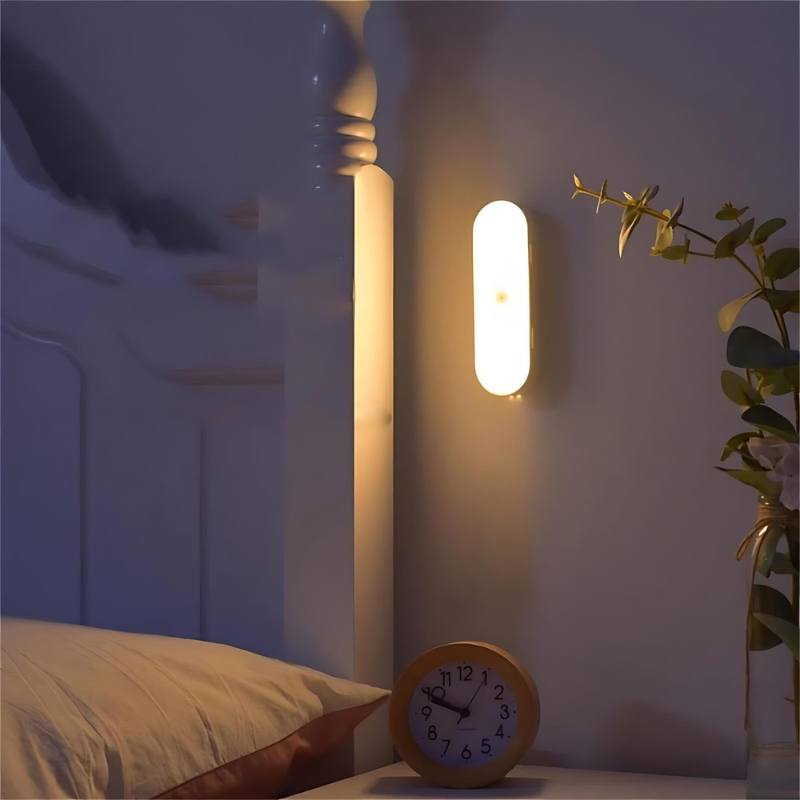 Wandmontiertes Nachtlicht neben Bett und Pflanze, spendet weiches Licht im Schlafzimmer

