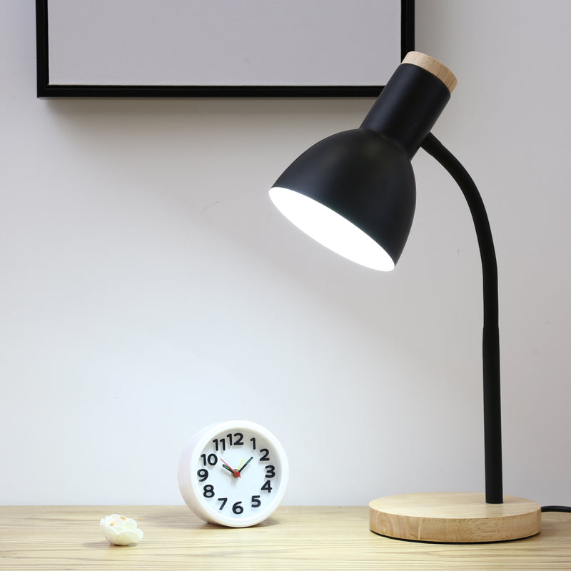 Schwarze LED-Lampe auf Holzsockel neben kleiner Weltuhr