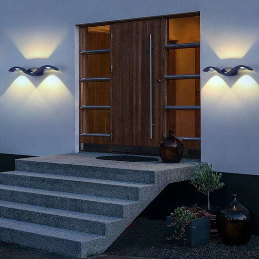 Zwei geschwungene Außenwandleuchten mit Up-&-Down-Light neben modernem Hauseingang