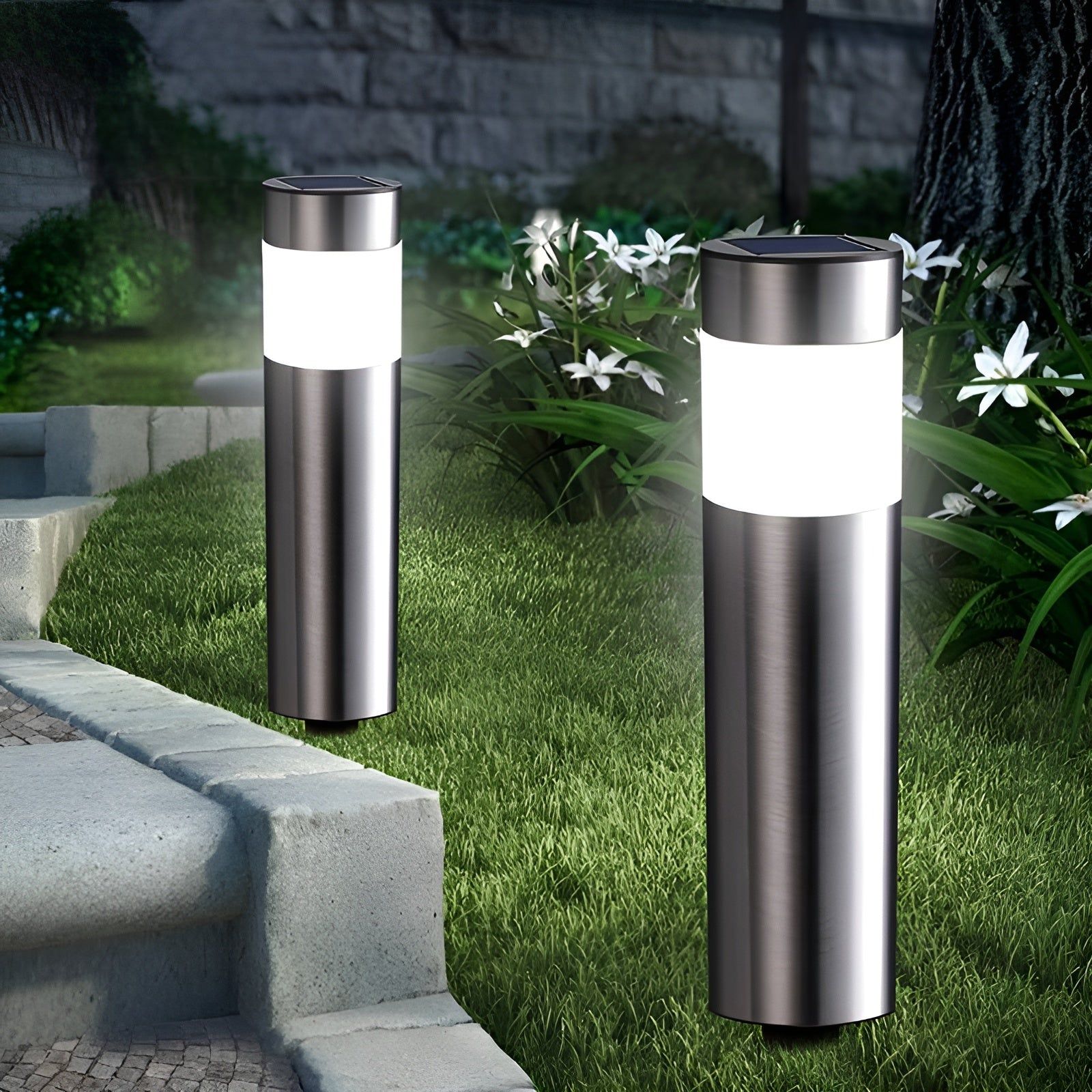 Zwei Edelstahl-Solarleuchten mit weißem Leuchtkörper auf Rasen neben Gartenweg